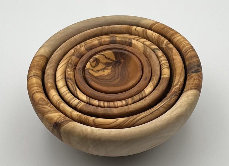 A set of wooden nesting bowls in various sizes and shades of natural wood.